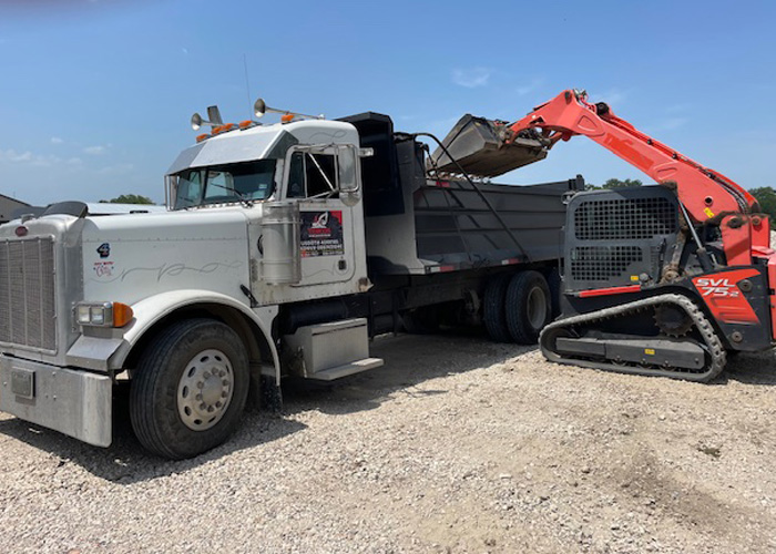 Skid steer loading gravel into a dump truck