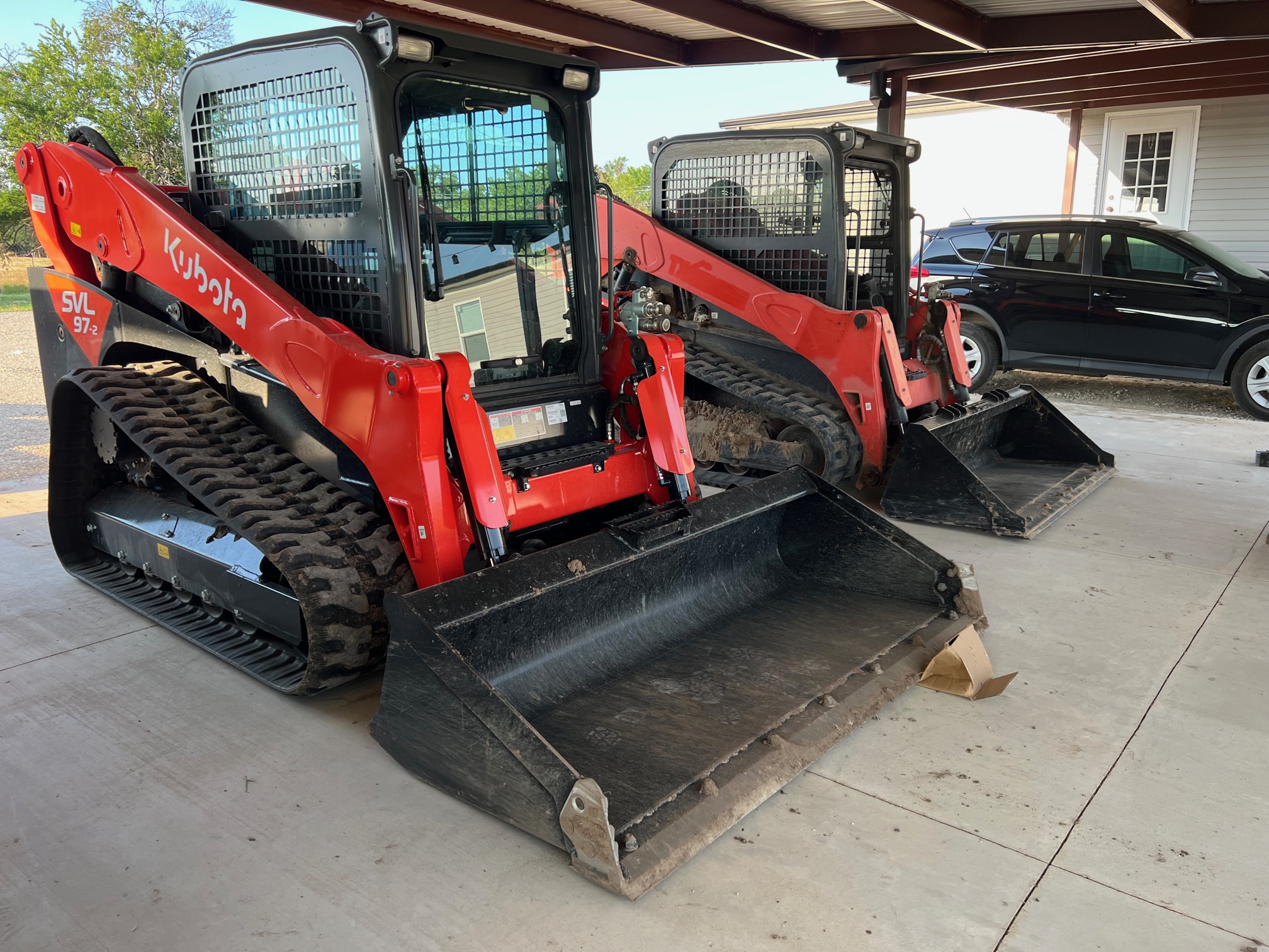 4 the twin skids Two red and black Kubota skid steers parked together
