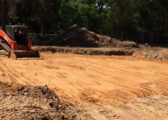 Orange skid steer on a cleared and graded area