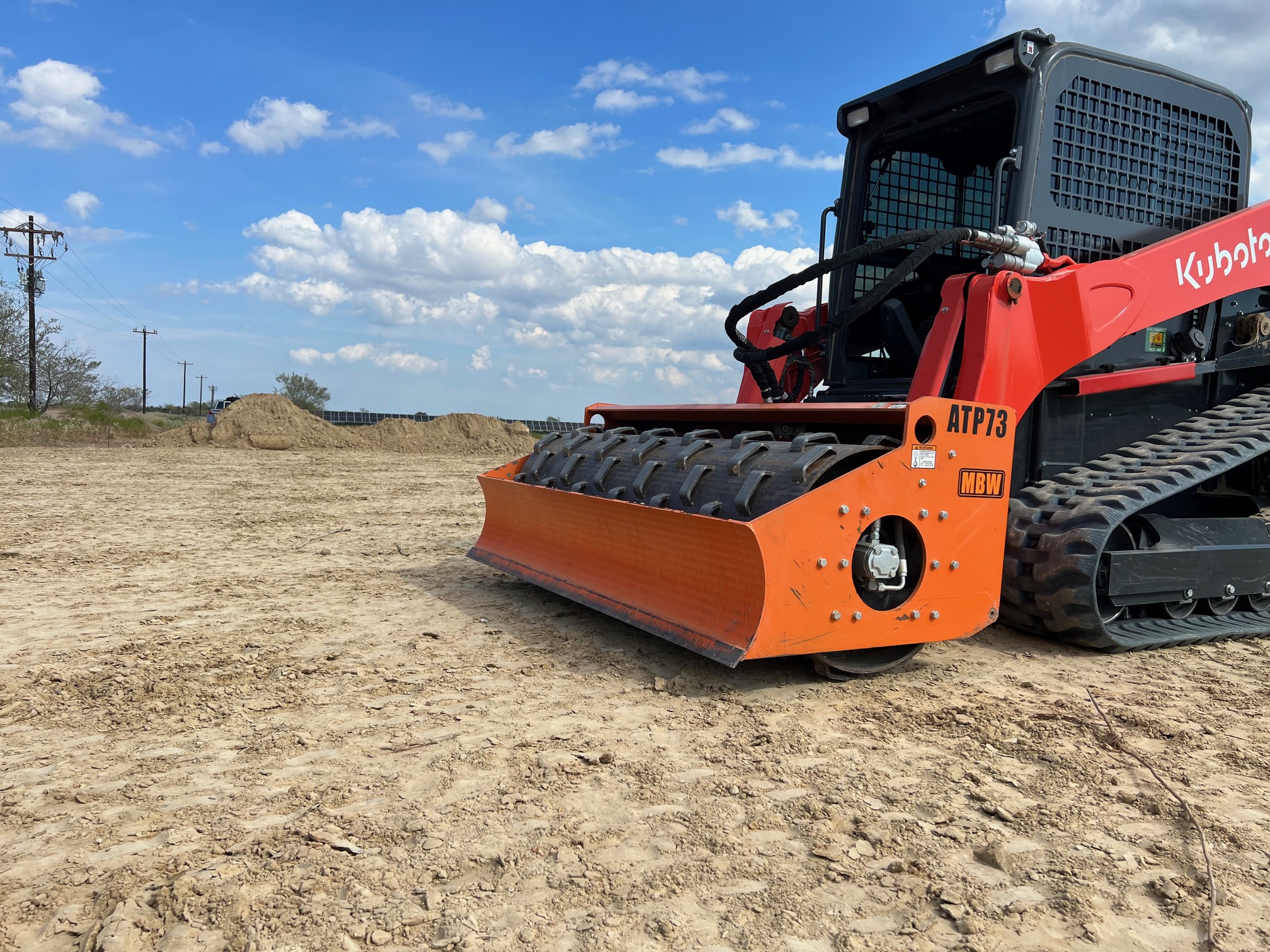 Copy of IMG_0321 Red and black Kubota skid steer with a roller attachment