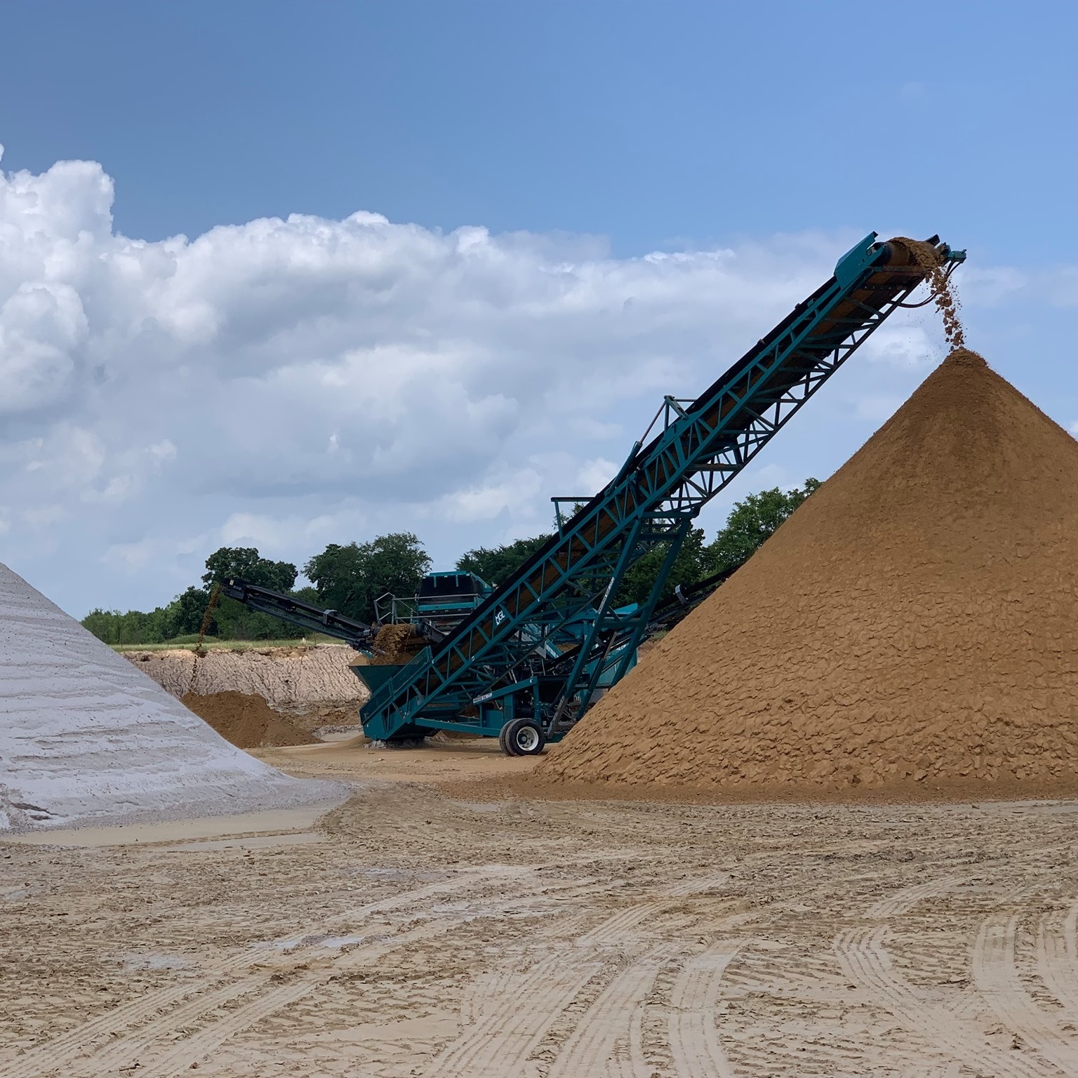 Cushion Sand Gravel processing machine creating a large mound of sand